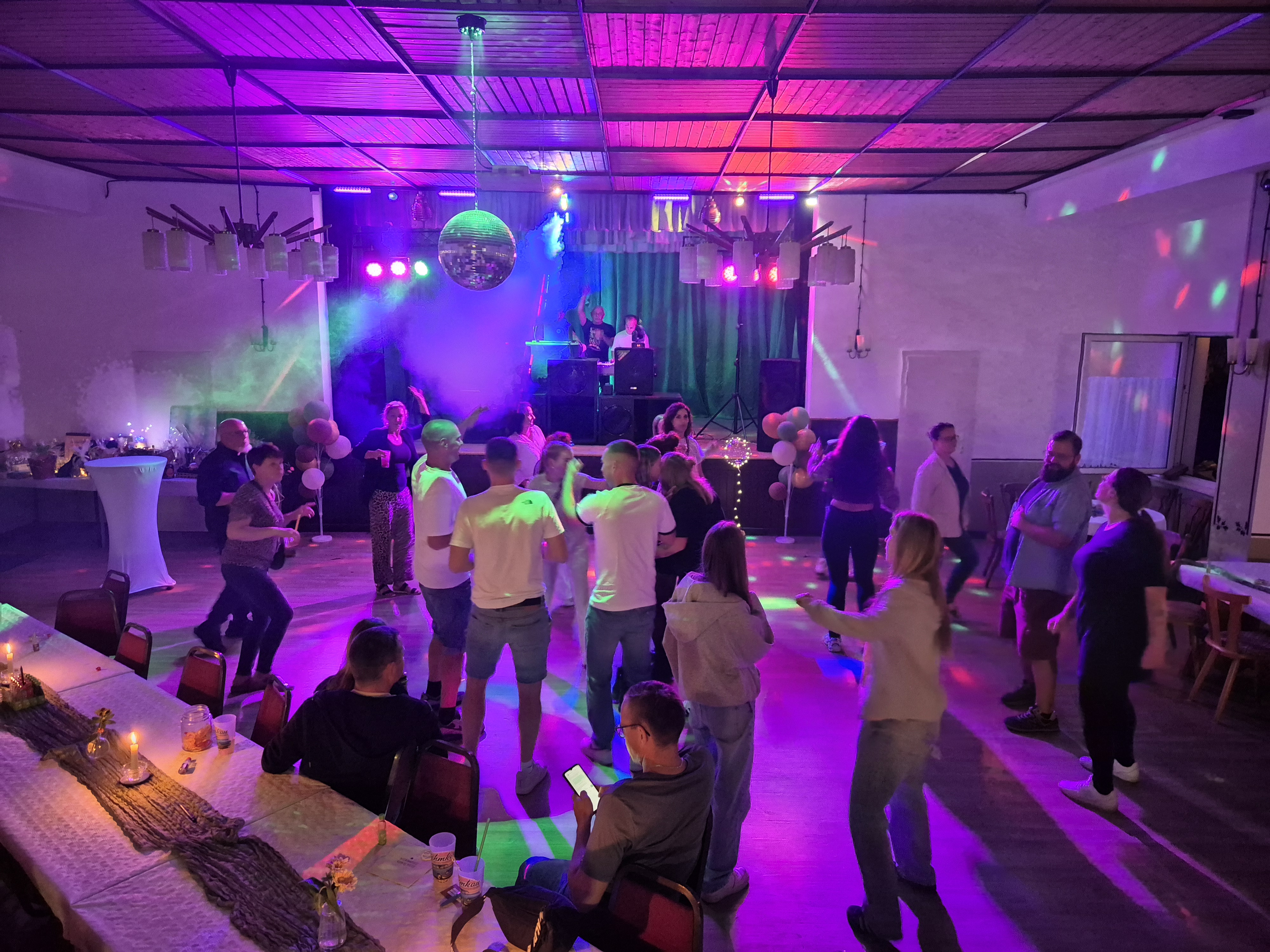 Gäste tanzen im Saal vor der beleuchteten Bühne.